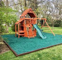 A wooden playground with a slide and swings in a backyard.