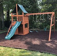 A wooden swing set with a slide and swings in a backyard.