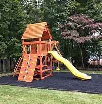 A wooden playground set with a yellow slide and climbing wall.