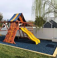 A wooden playground with a yellow slide and a climbing wall.