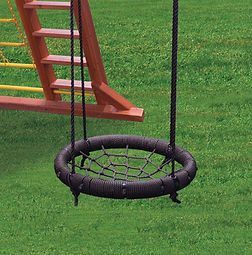 A tire swing is hanging in the grass next to a wooden ladder.