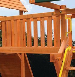 A wooden playground with a yellow ladder and a green roof.