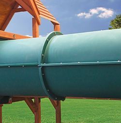 A green slide is sitting in the middle of a lush green field.