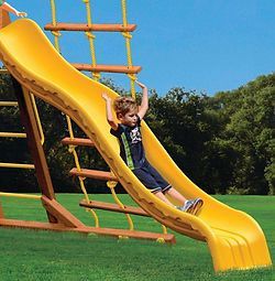A young boy is riding down a yellow slide on a playground.