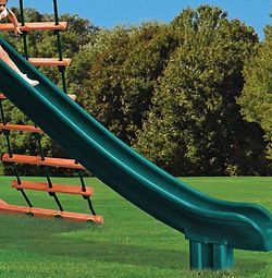 A child is riding down a green slide on a playground.