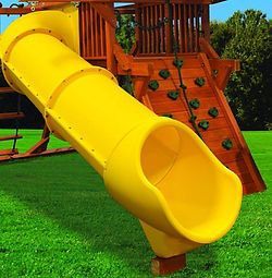 A yellow slide is sitting on top of a lush green field.
