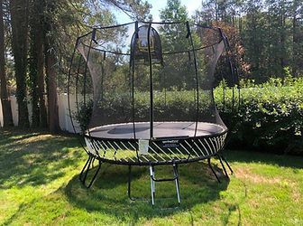 A large trampoline is sitting on top of a lush green lawn.