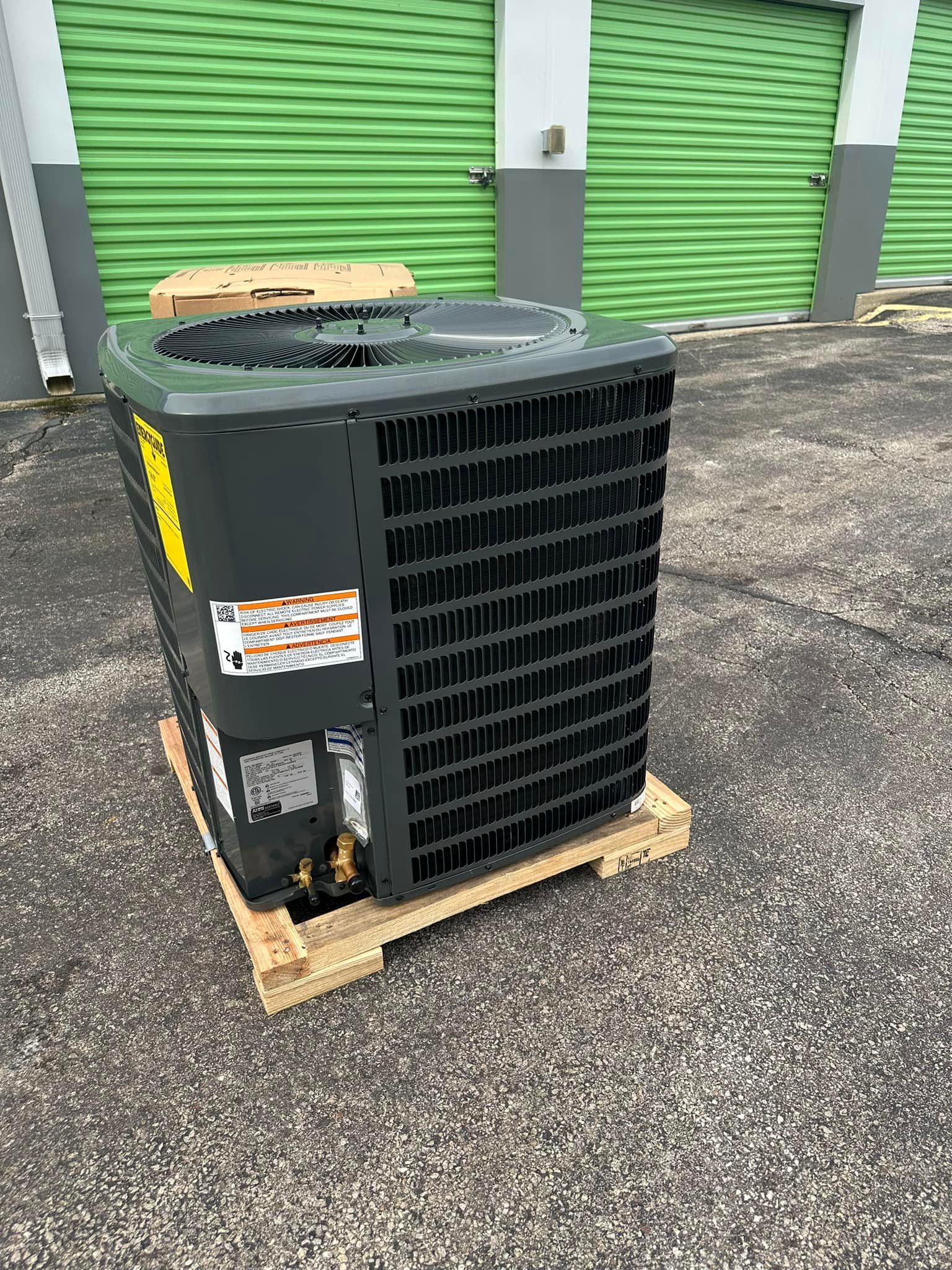Outdoor HVAC unit on wooden pallet in front of green storage unit doors
