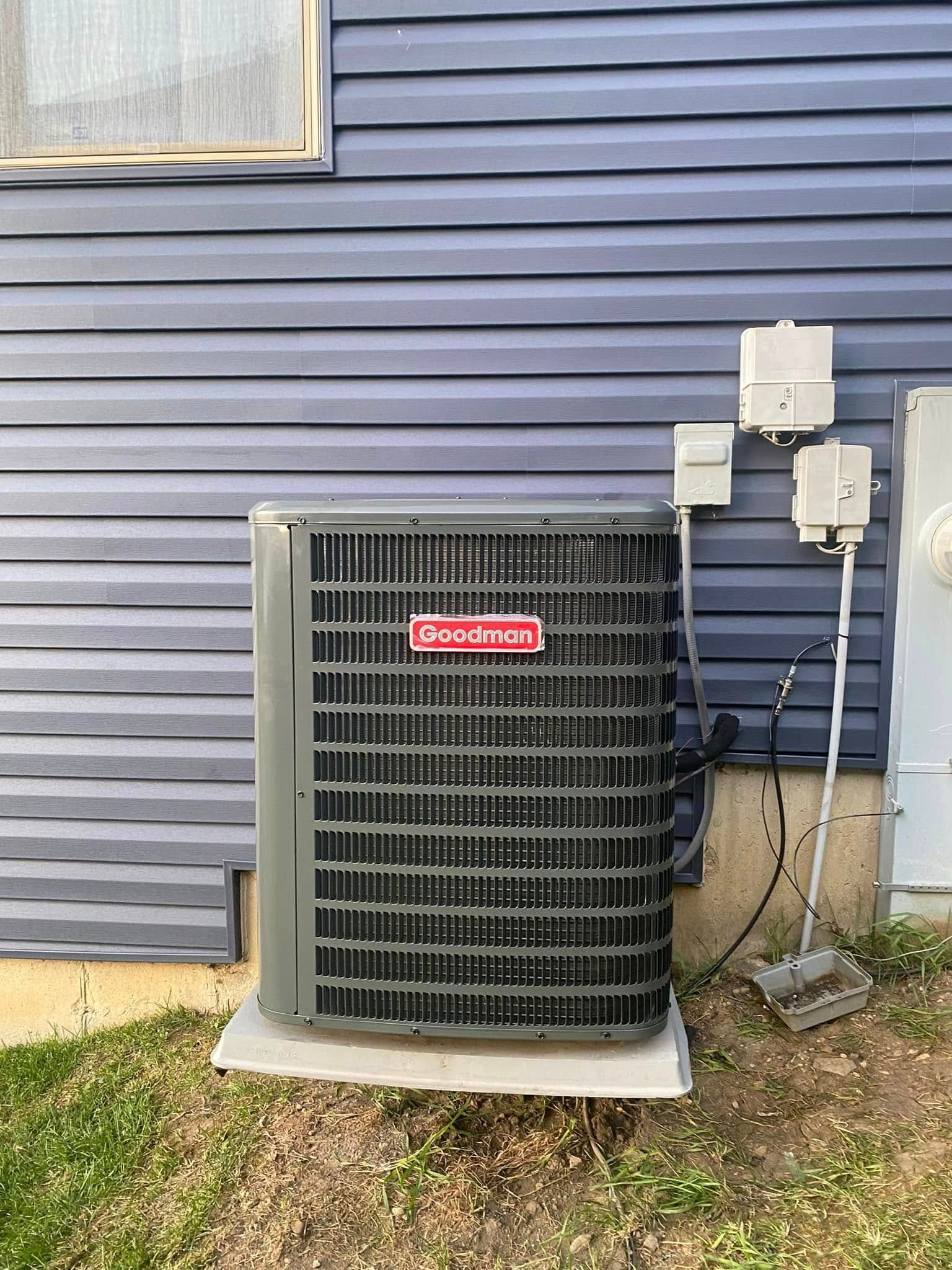 Outdoor air conditioner unit beside a blue vinyl-sided house with electrical boxes and conduit