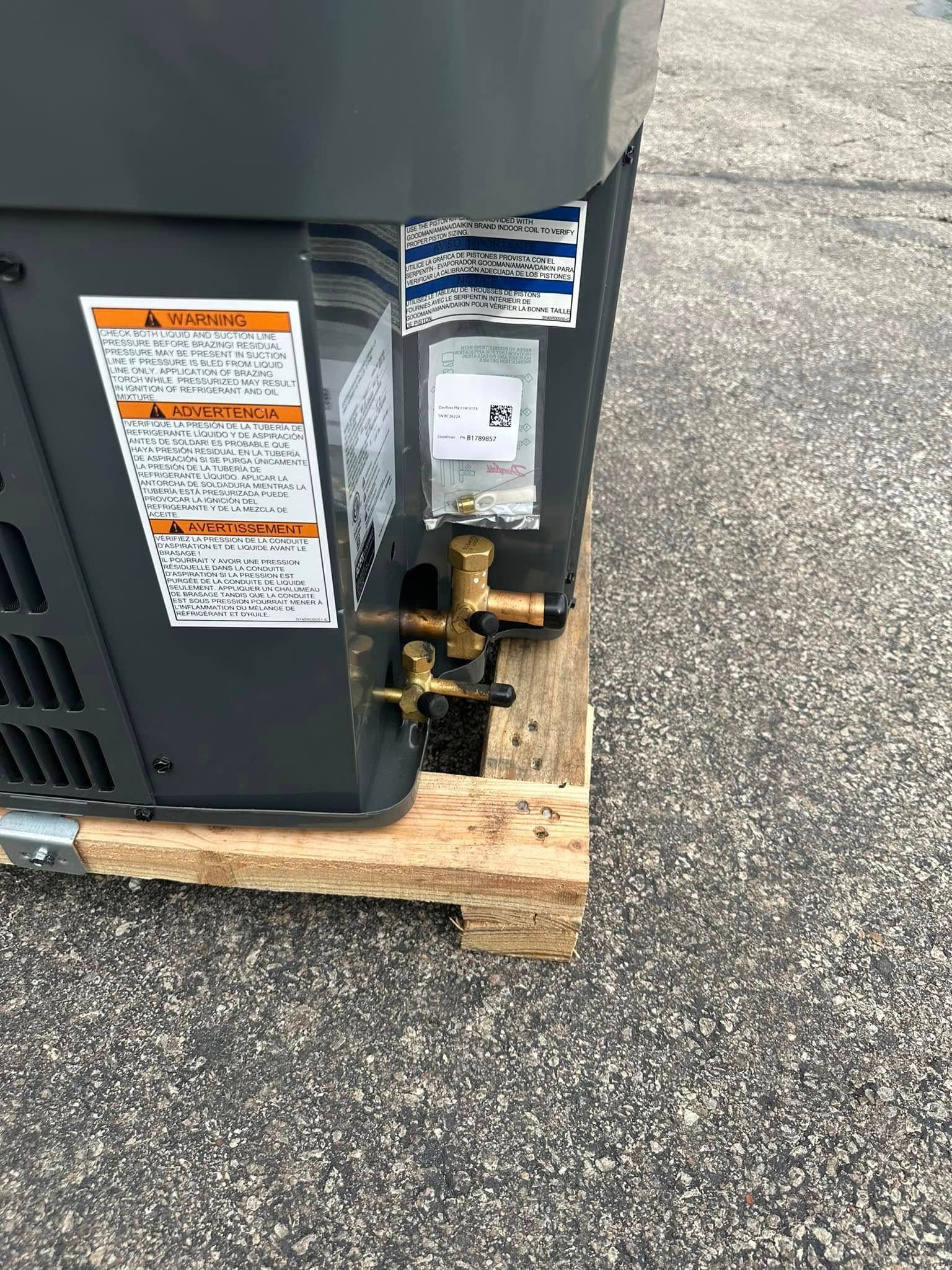 Close-up of a gas appliance’s side, with a rusted valve and black hose on a wooden base outdoors.