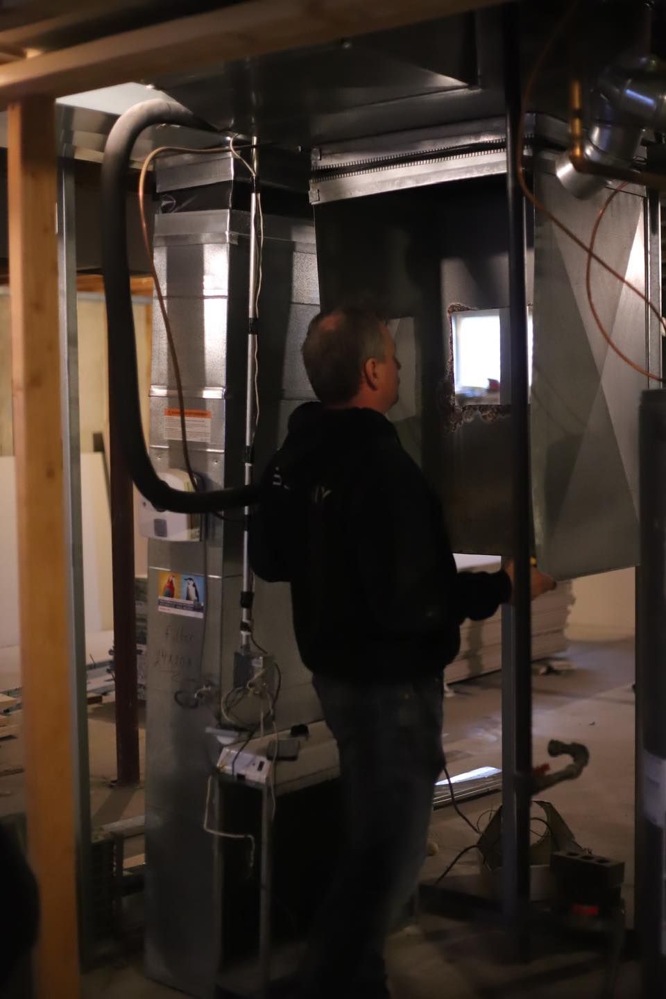 Person standing in an industrial room beside a large metal machine and ducting