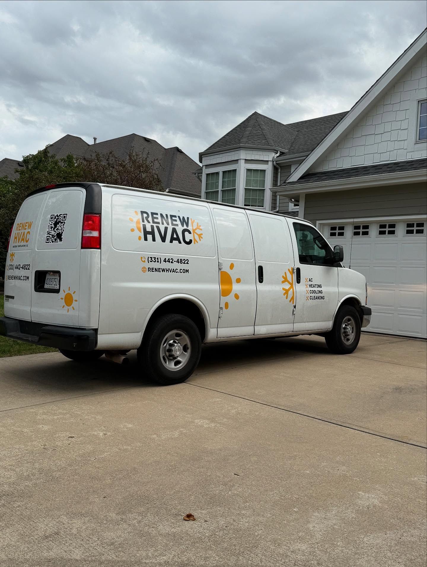 White Premier HVAC service van parked in a residential driveway beside a house and garage.