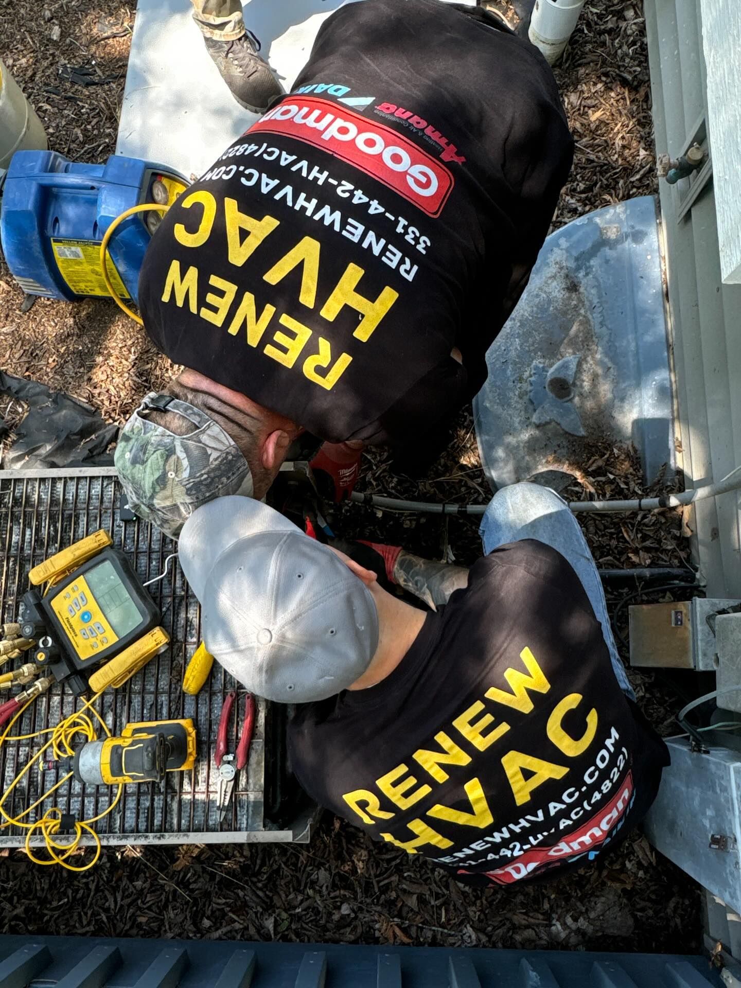 Two rescue workers in black and yellow gear kneel over a person on the ground amid debris and tools.