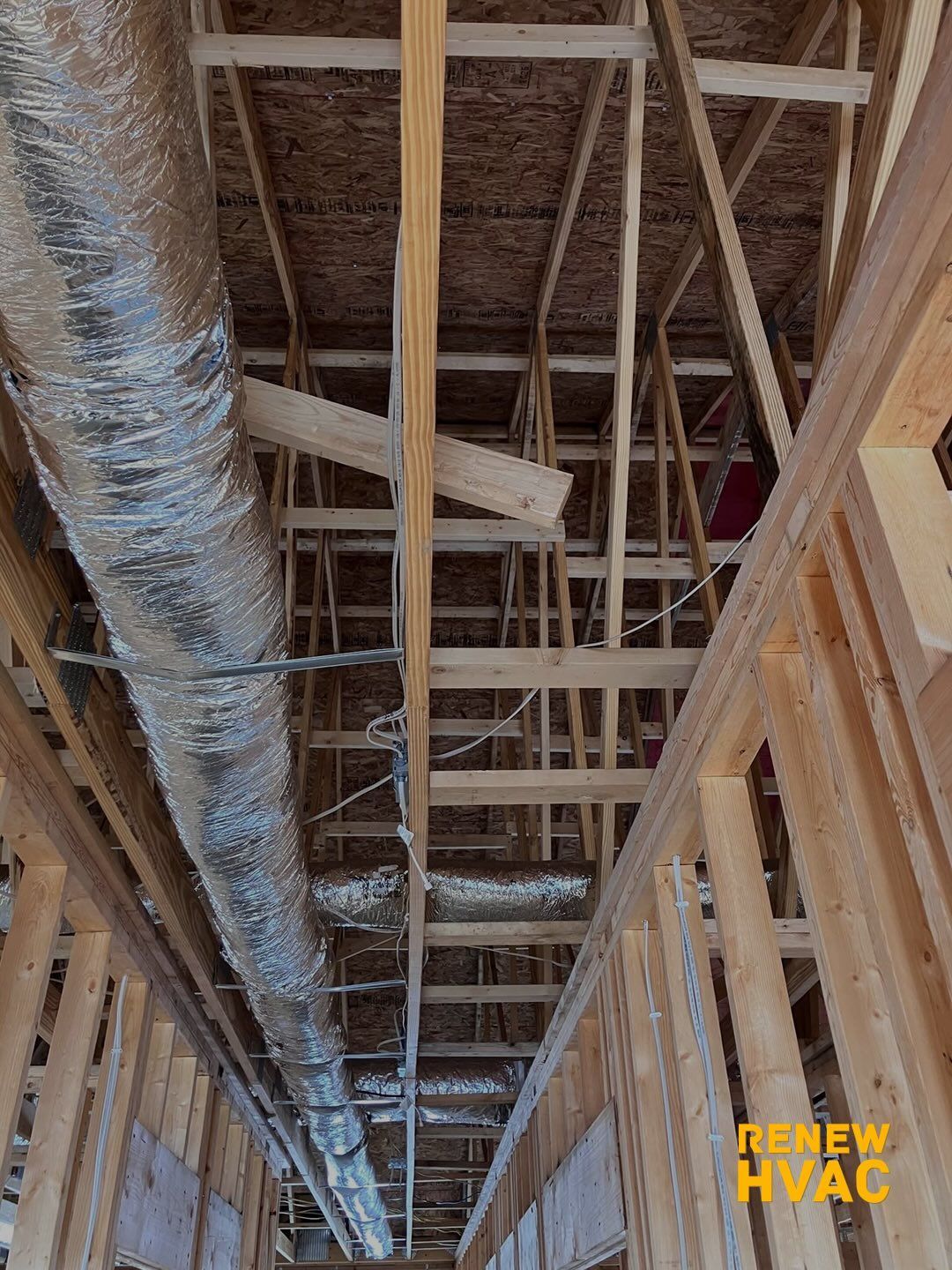 Exposed ceiling framing and ductwork inside a building under construction