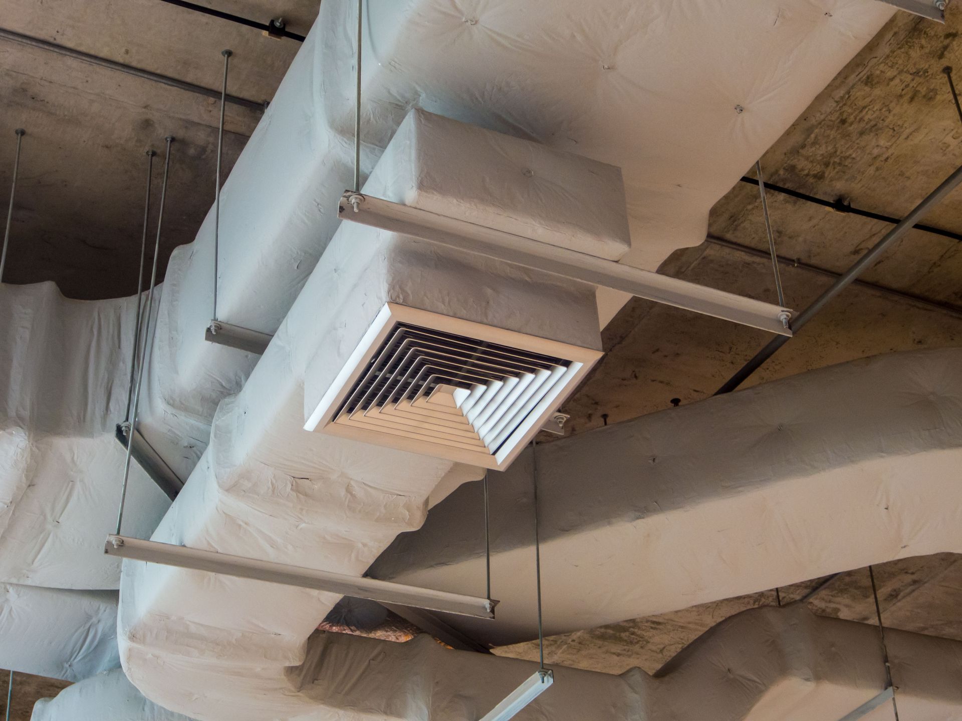 Ceiling HVAC duct with a square vent in an unfinished industrial interior