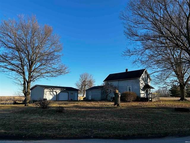 A man is walking in front of a house with a blue sky in the background