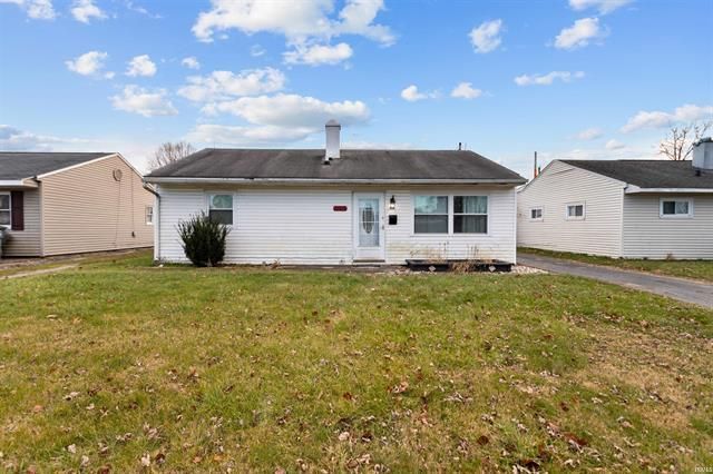 A white house with a black roof is sitting on top of a lush green lawn