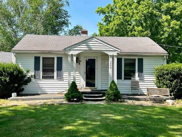 A white house with a porch and a bench in front of it