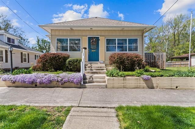 A house with a blue door and purple flowers in front of it