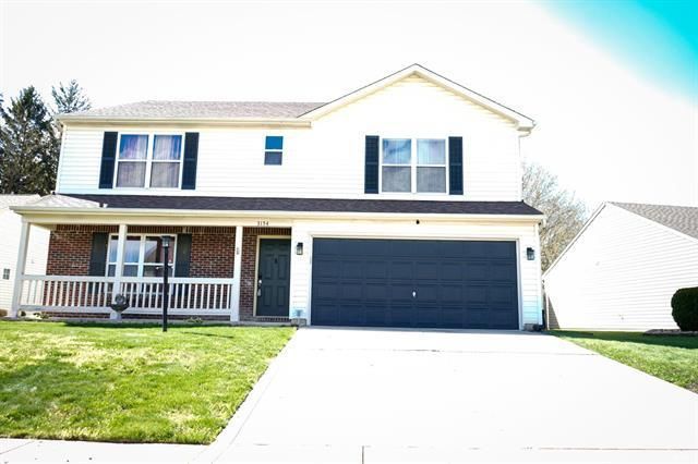 A large white house with a black garage door and a porch