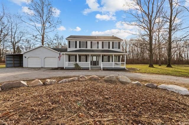 A large white house with a porch and a garage is for sale
