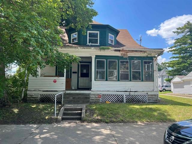 A white house with a green roof and a car parked in front of it