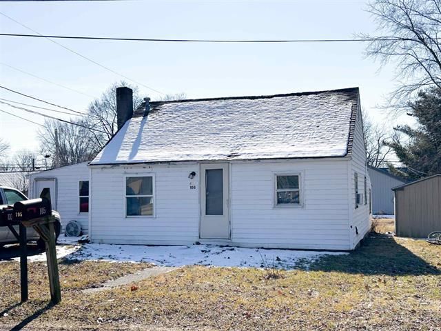 A small white house with snow on the roof is for sale