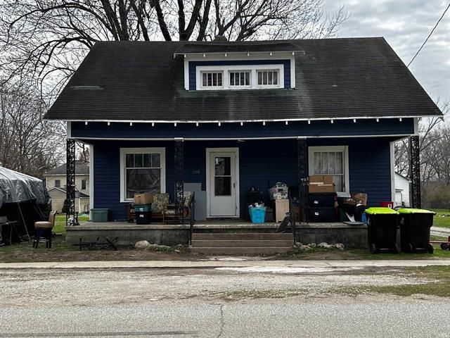 A blue house with a black roof is sitting on the side of the road