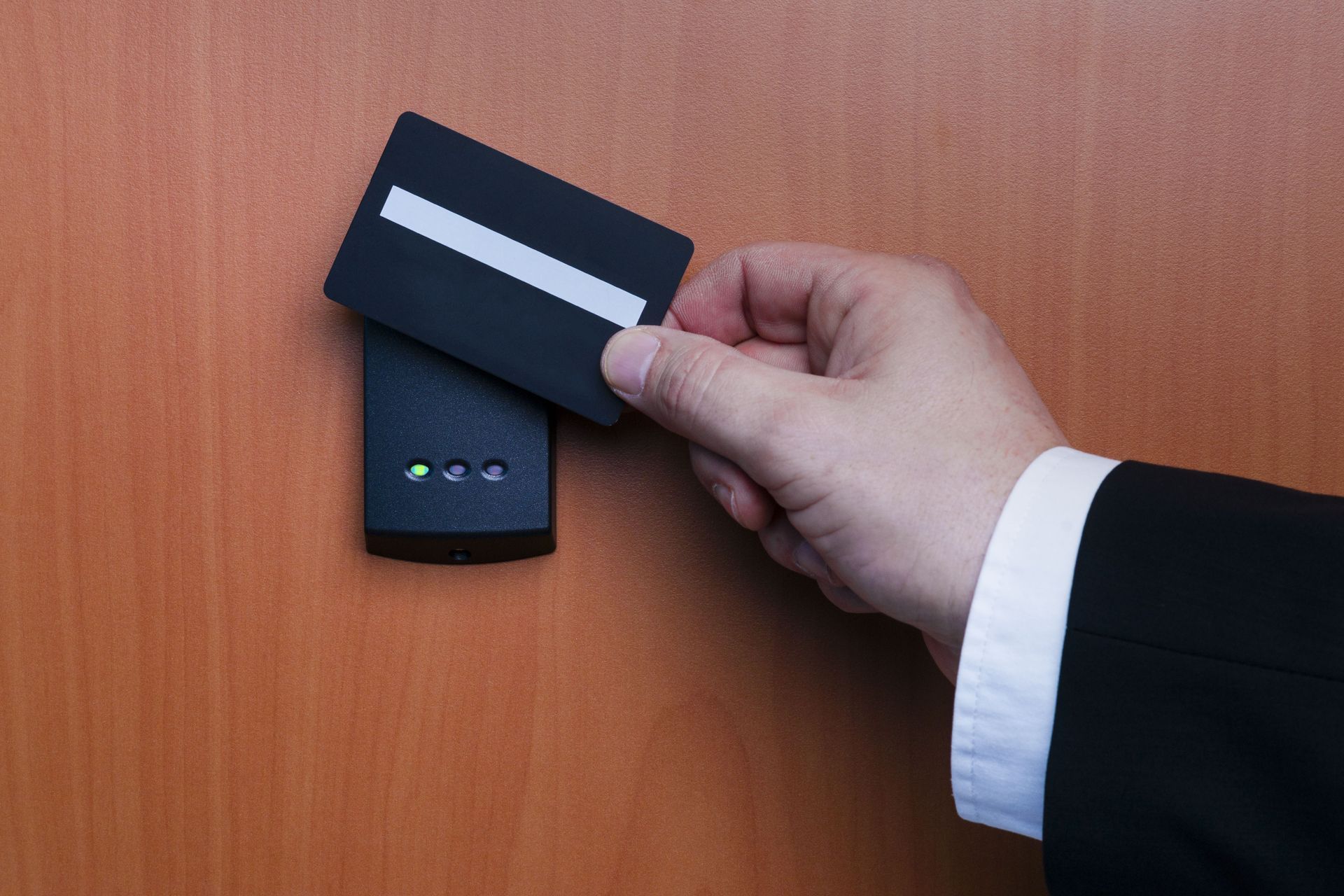 Hand holding a keycard to open a door lock with green indicator lights