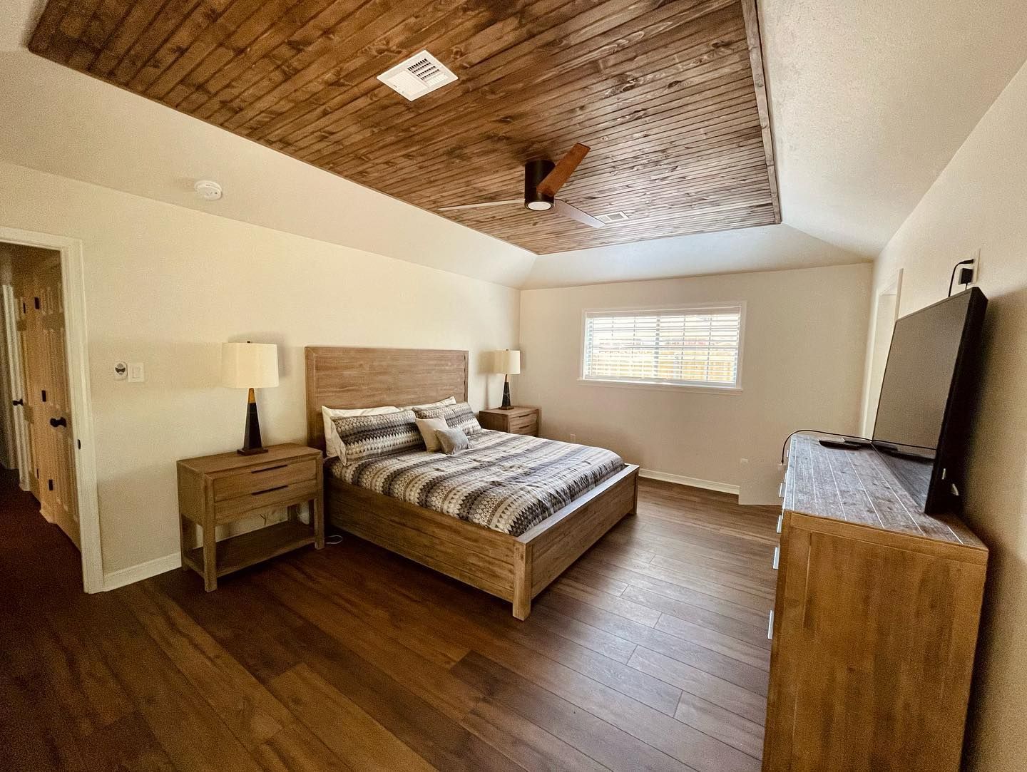 A bedroom with a bed , nightstand , dresser and television.