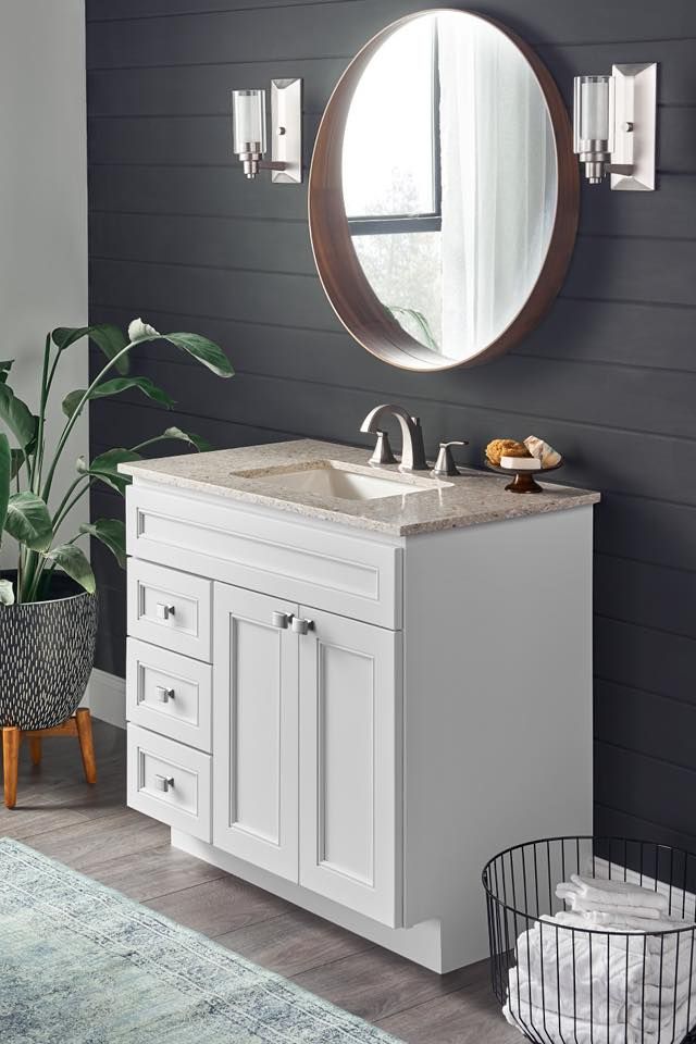 A bathroom with a white vanity , sink and mirror.