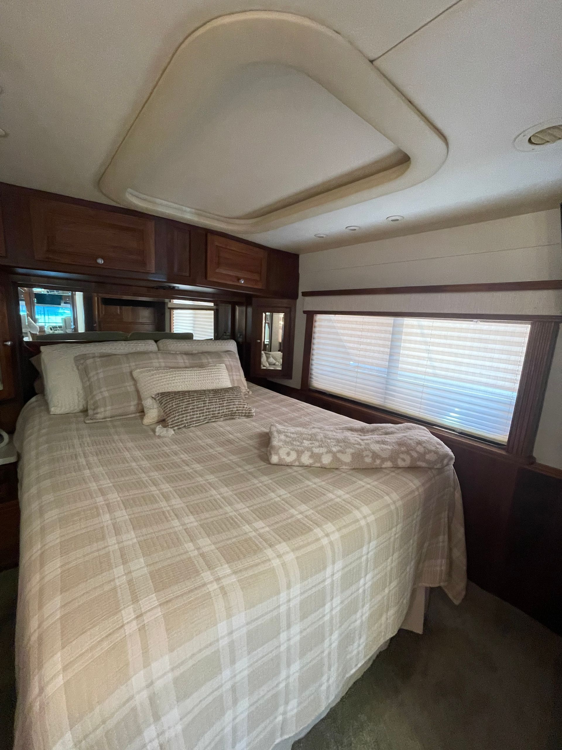 A bedroom in a rv with a bed and a window.