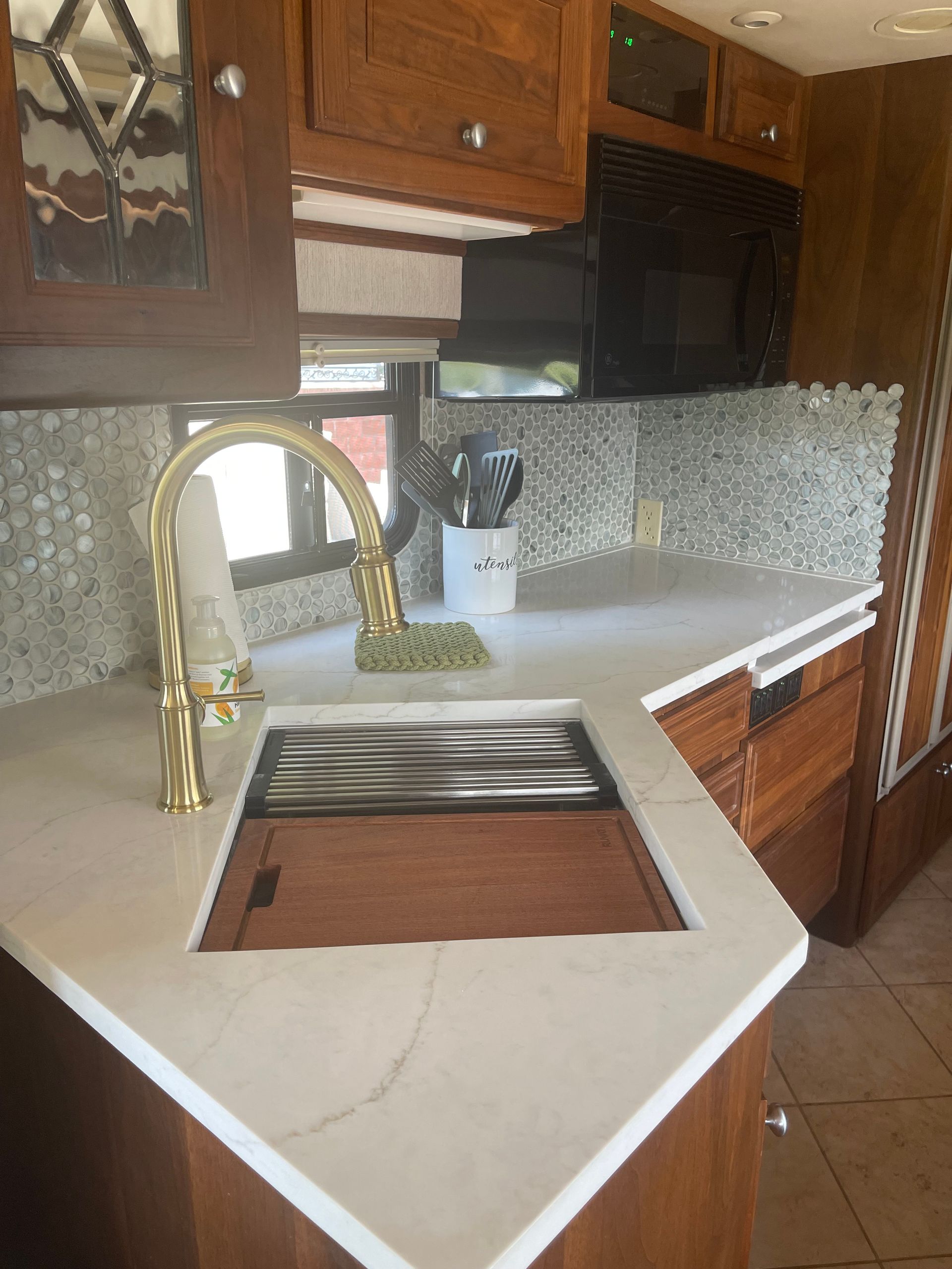 A kitchen with a sink , faucet and microwave.