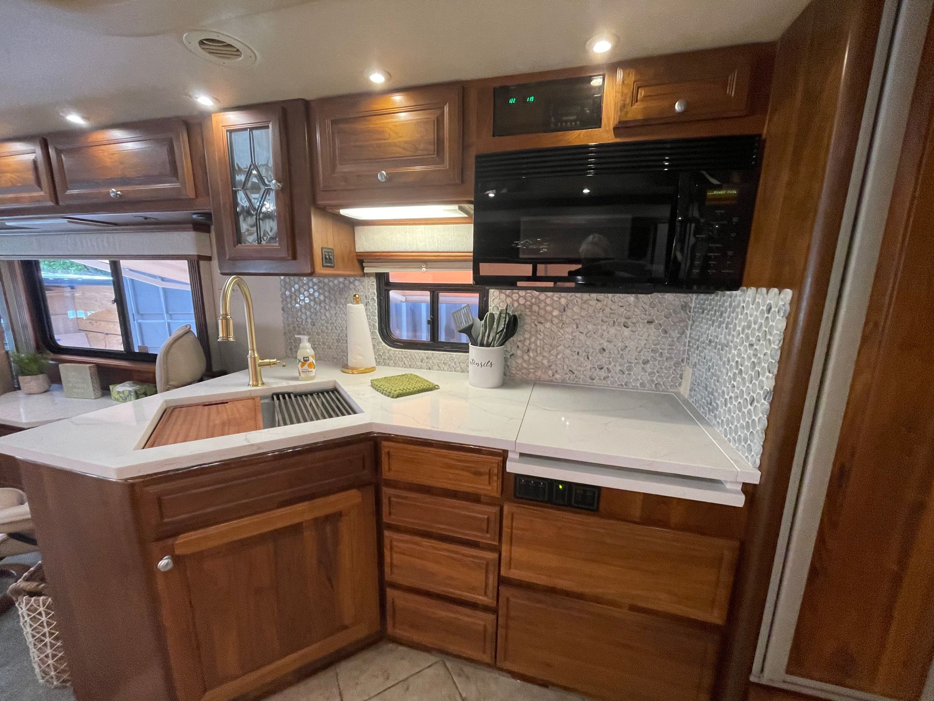 A kitchen in a rv with wooden cabinets and a sink.