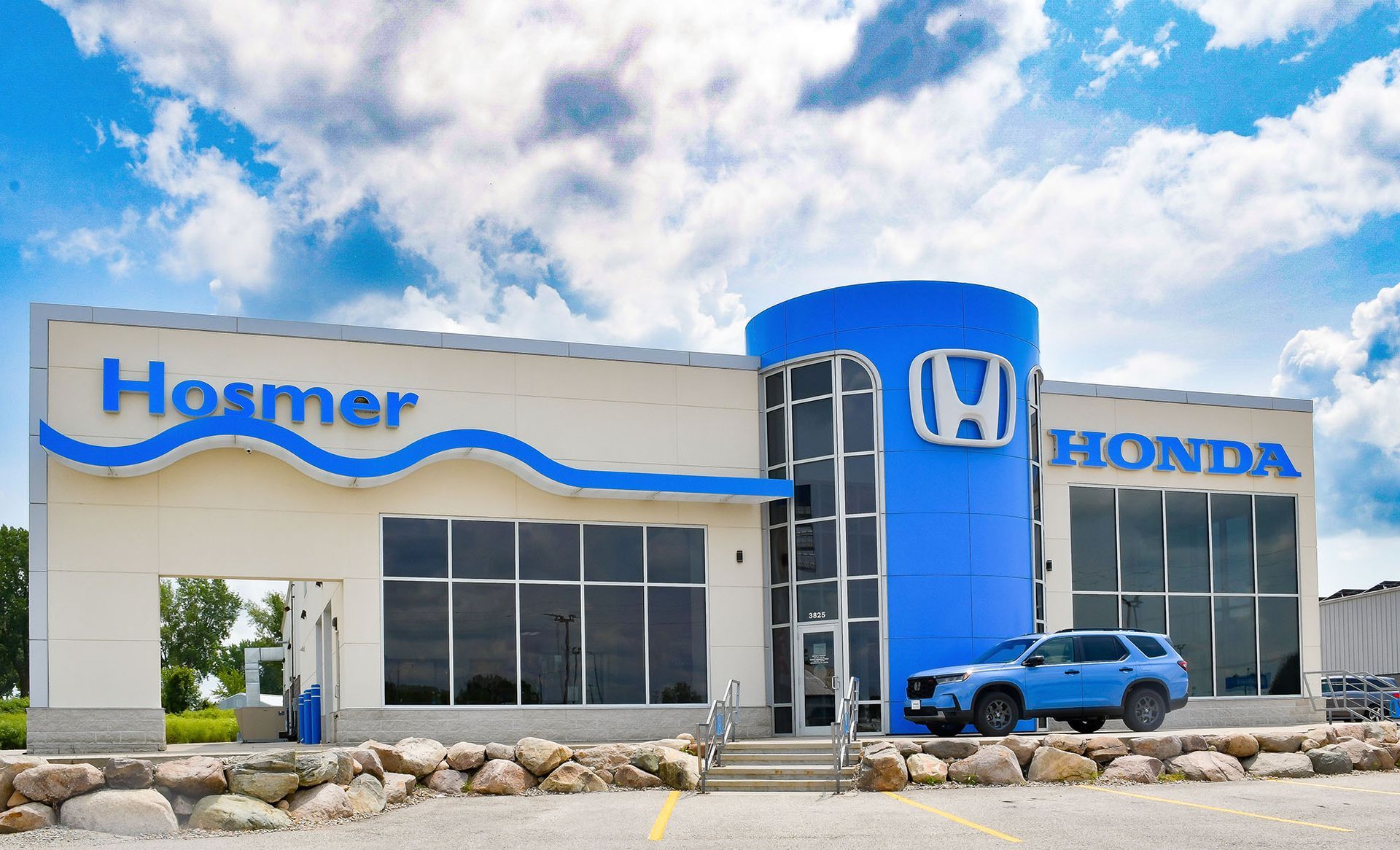 A honda dealership with a blue car parked in front of it