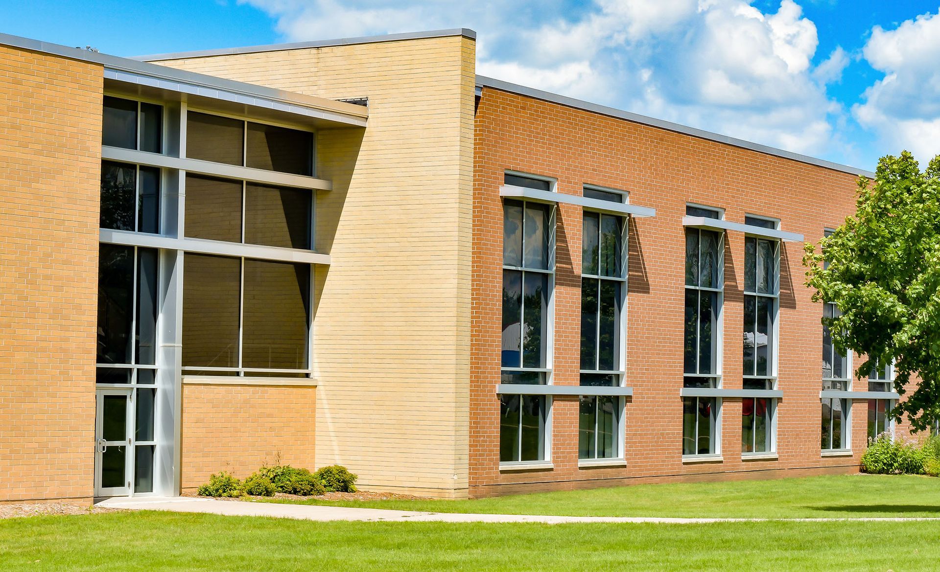 A large brick building with a lot of windows and a tree in front of it