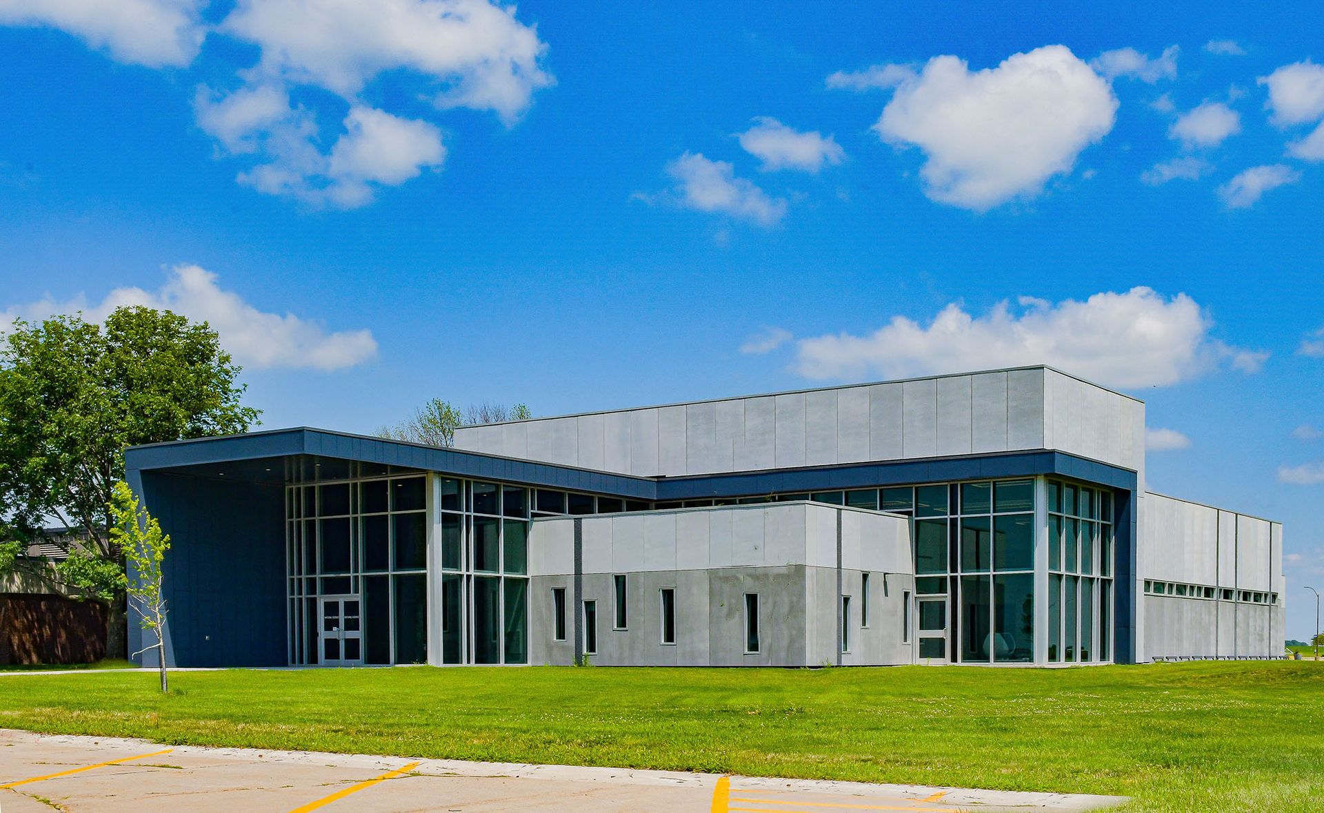 A large building with a lot of windows is sitting on top of a lush green field.