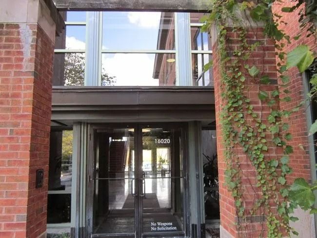 Glass-paned entrance to a red brick building with vines growing on the right pillar.