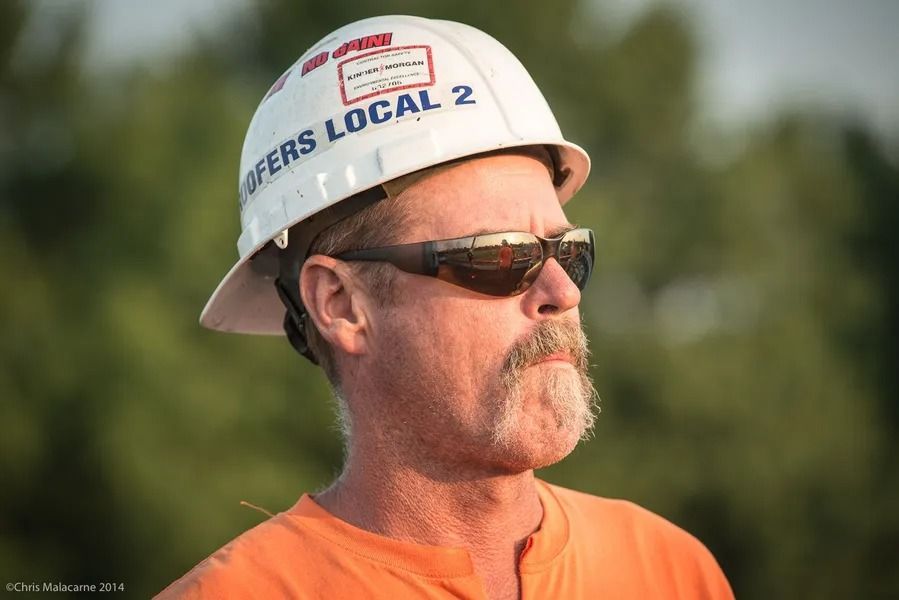 A construction worker wearing a white hard hat labeled 