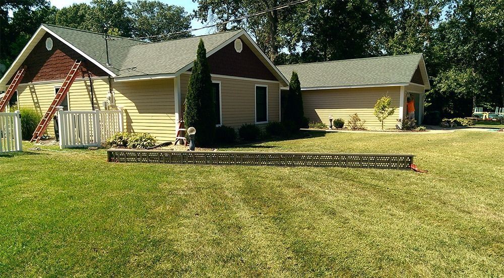 A suburban house under construction, with a ladder leaning against the roof and building materials laid on the lawn.