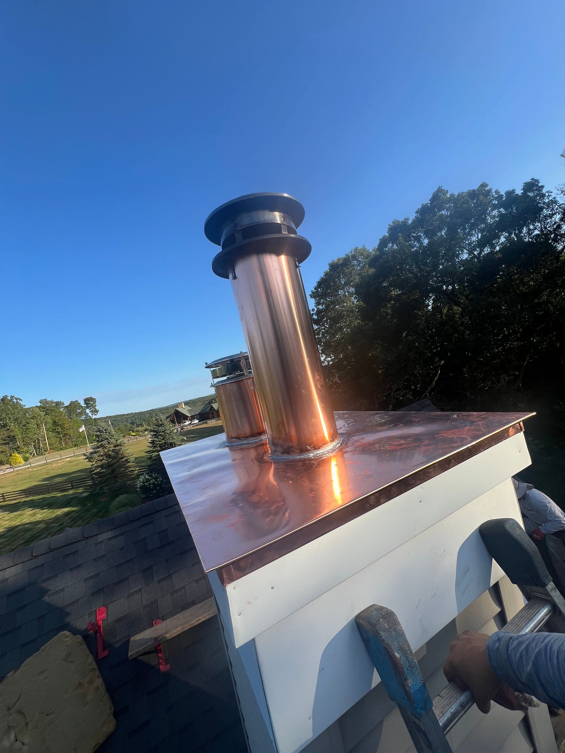 Copper chimney stack on a white structure with a blue sky background.