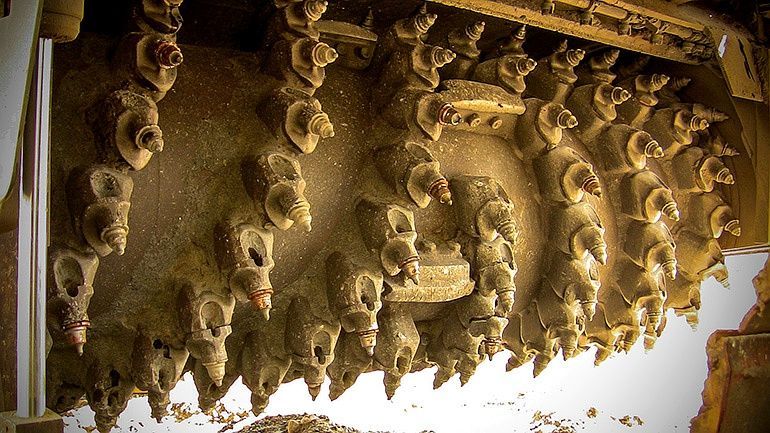 Close-up of ornate carved stone ceiling with dangling decorative details in warm light