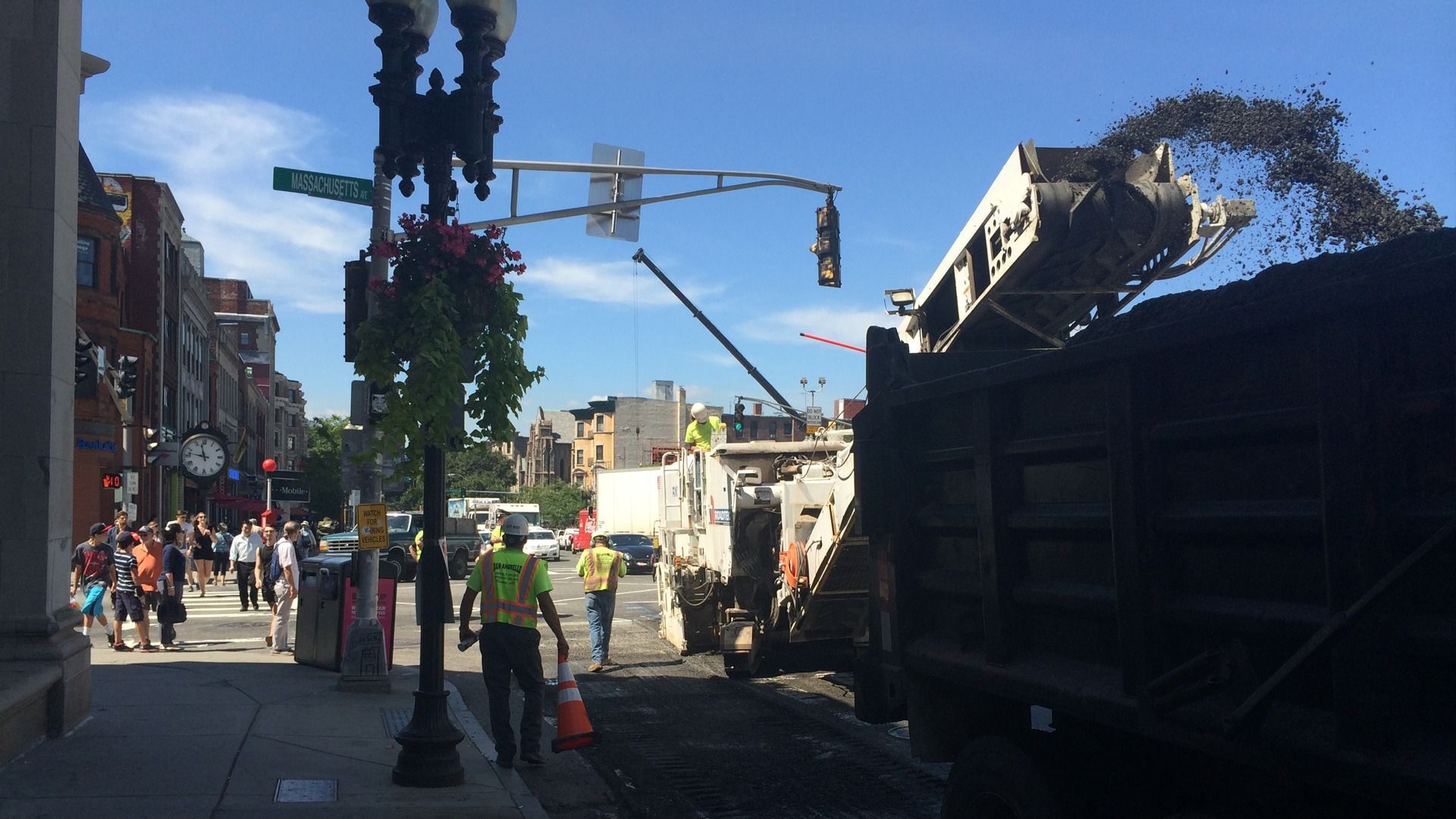Train derailment scene with workers in high-visibility vests beside a damaged rail car on a city street