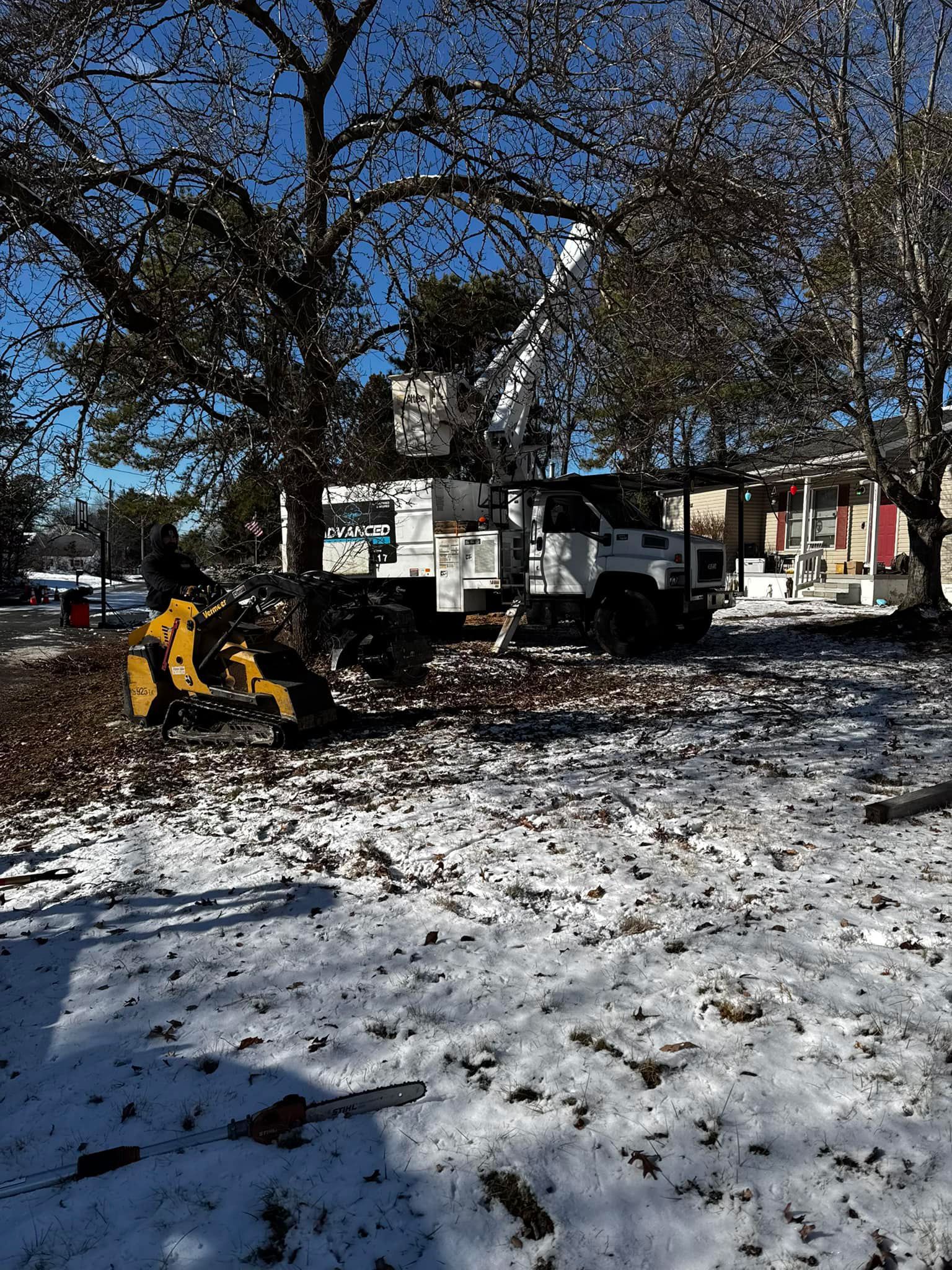 A tree stump grinder is sitting in the snow next to a truck.