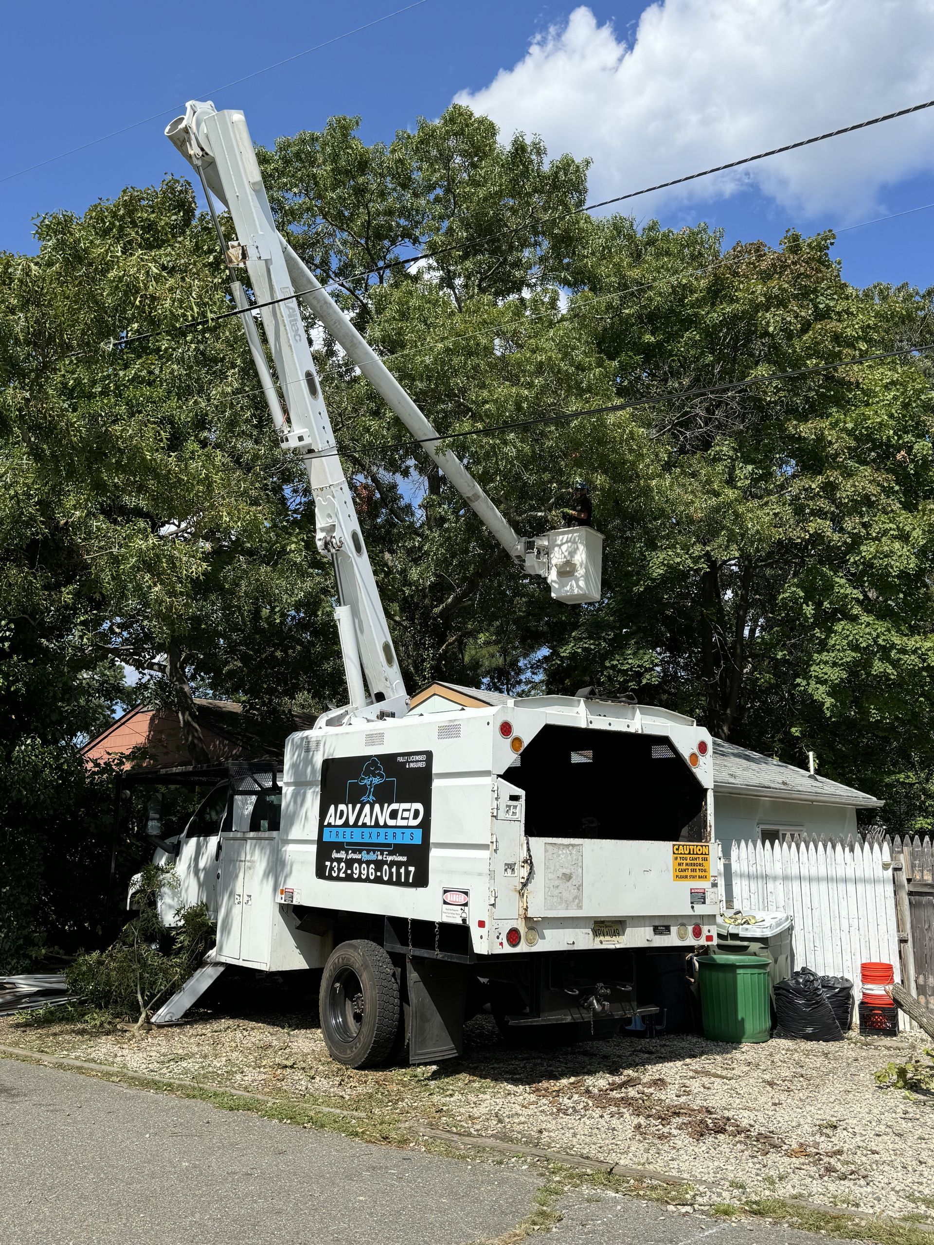 A tree trimming truck is parked in front of a house.