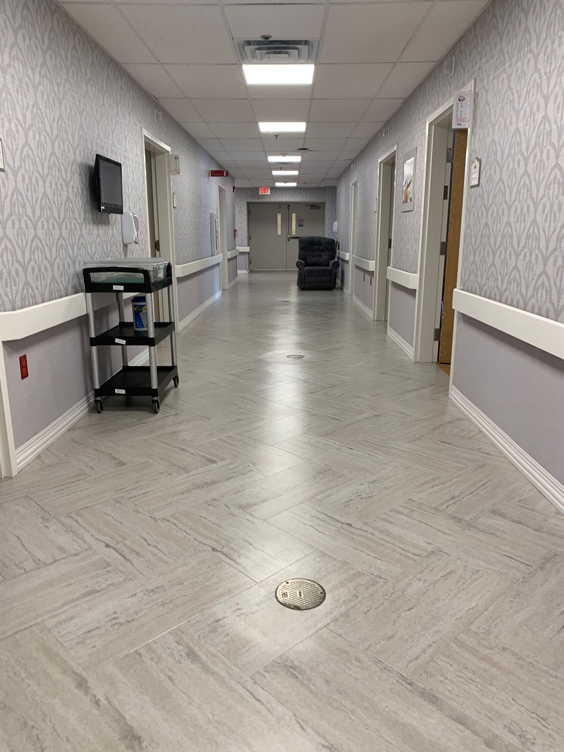 A long hallway in a hospital with a drain on the floor.