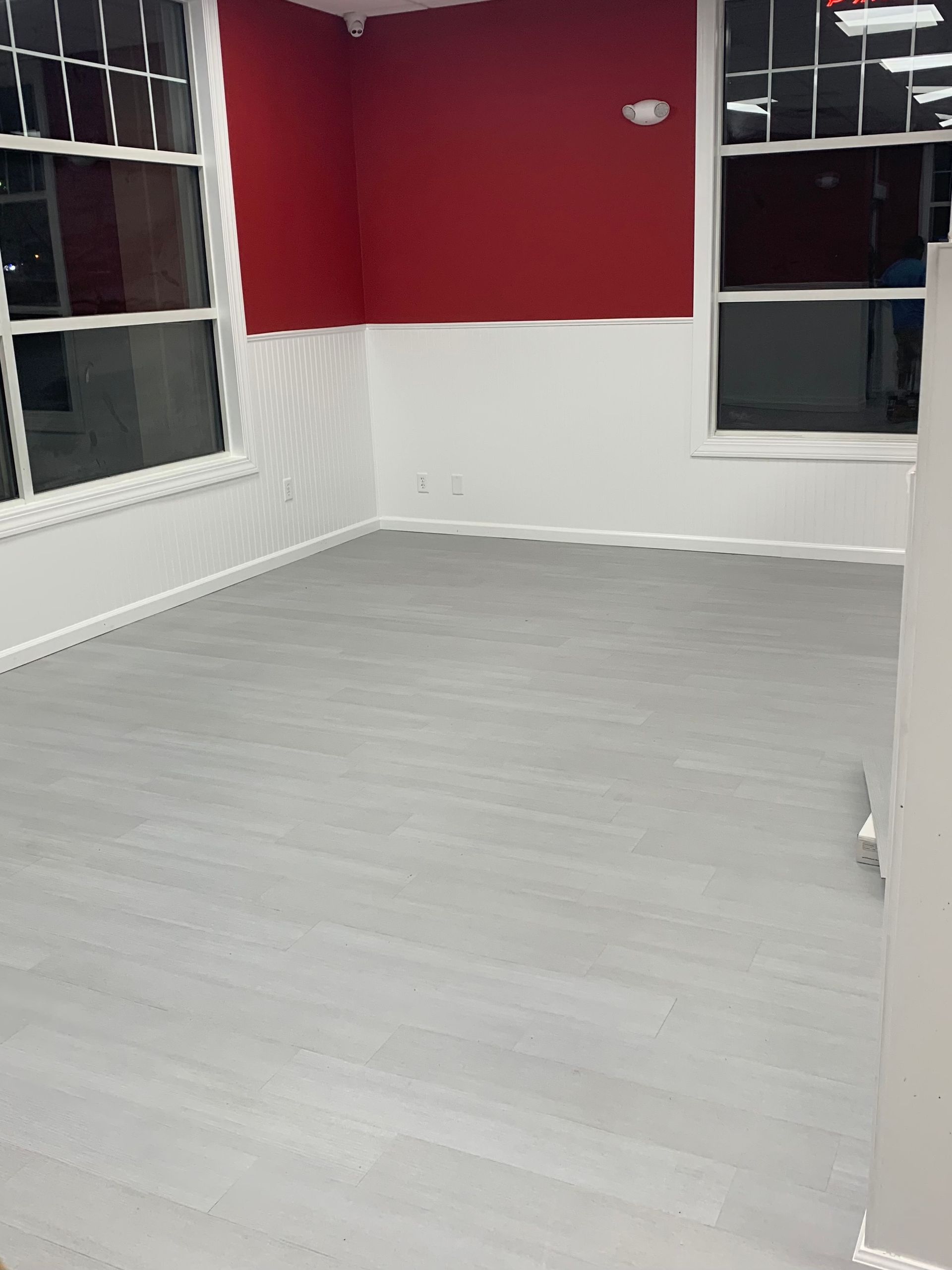 An empty room with a red wall and a new floor