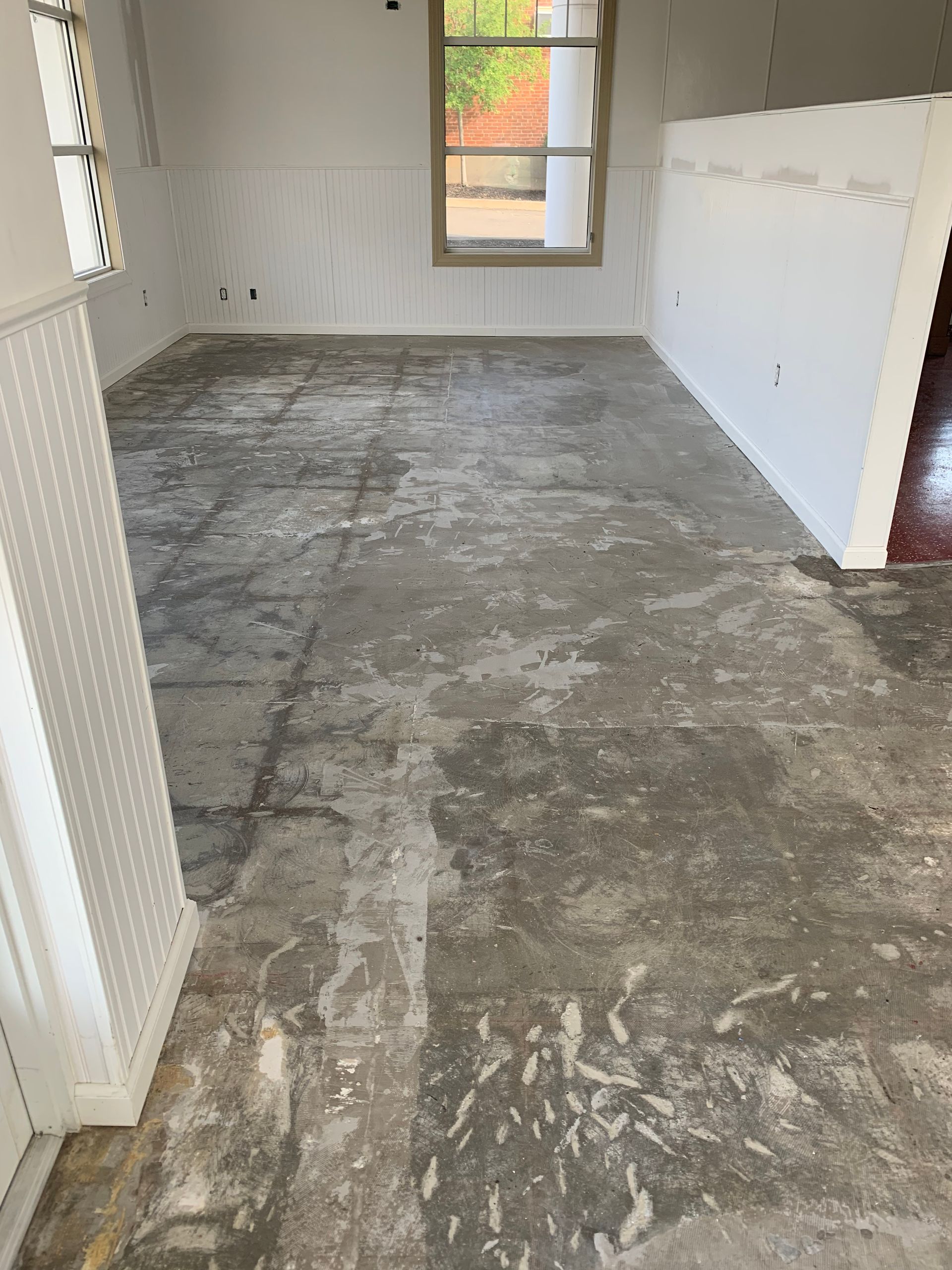 A room with an unfinished concrete floor and white walls