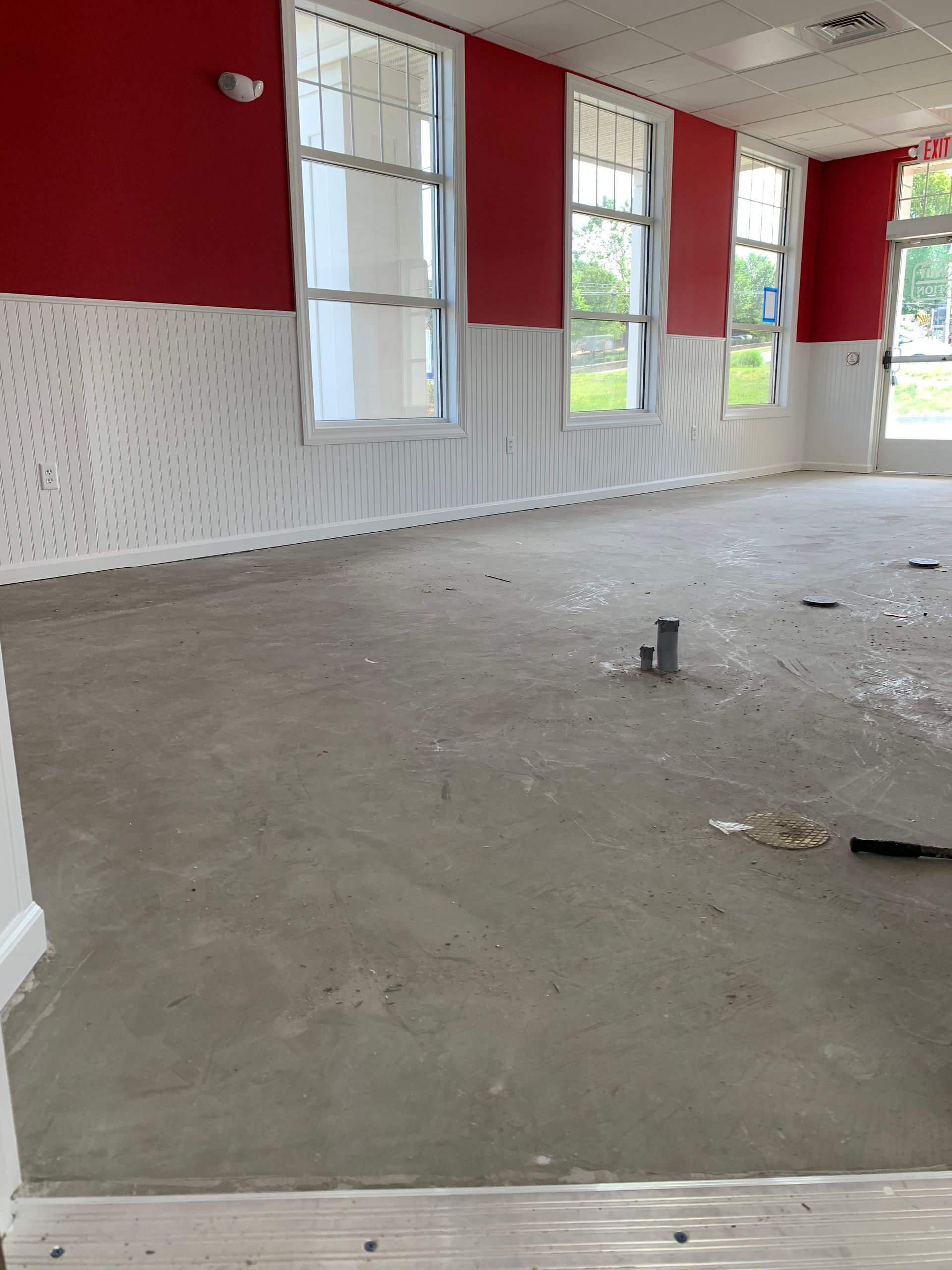 An empty room with red walls and white trim and an unfinished floor