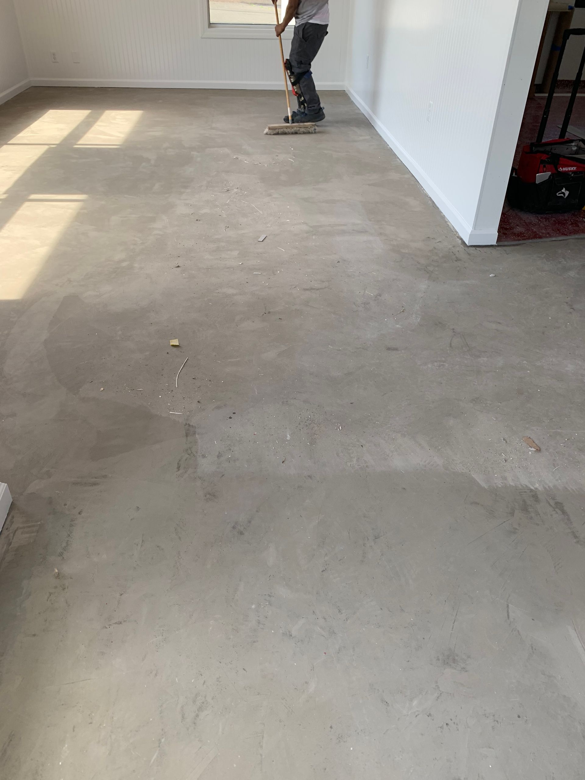 A man is standing on a concrete unfinished floor in a room